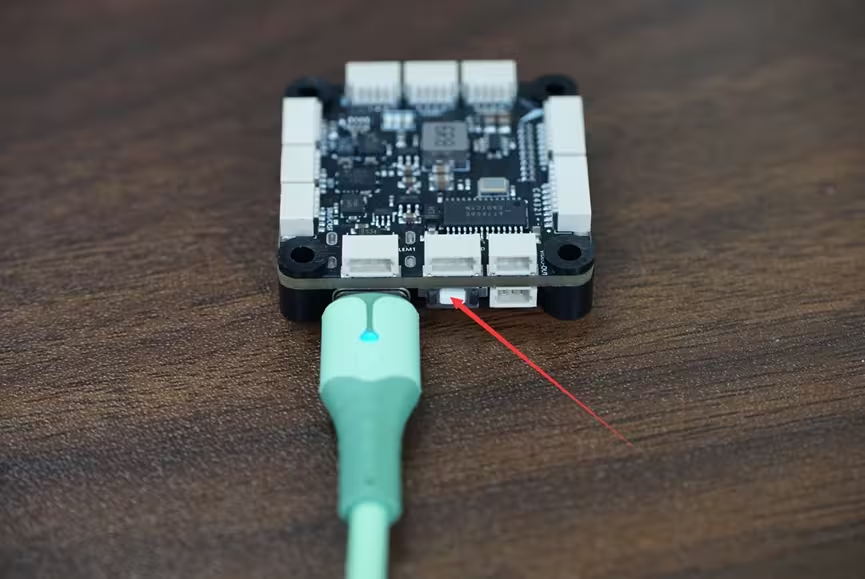 Holding the BOOT button next to the USB-C connector while plugging in the cable to enter DFU mode
